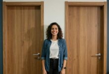 Pessoa confiante sorrindo diante de várias portas coloridas, representando novas oportunidades de recolocação profissional.