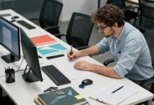 Profissional trabalhando em ambiente criativo e moderno rodeado de materiais de arte e tecnologia