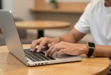 Pessoa moderna trabalhando com notebook em um café descontraído, representando a flexibilidade dos empregos com jornada flexível.