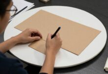 Pessoa concentrada trabalhando sozinha em um ambiente tranquilo e moderno, rodeada por materiais de trabalho e notas organizadas