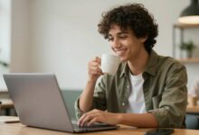 Jovem sorridente trabalhando com laptop e café em um ambiente moderno, representando satisfação com empregos de meio período