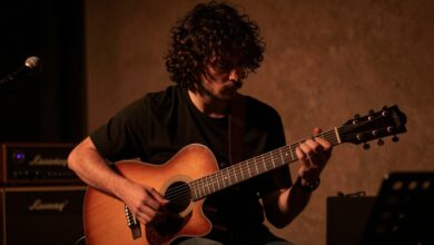 Um músico apaixonado tocando guitarra em um palco com iluminação dramática, simbolizando o sonho e a dedicação da carreira musical.