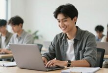 Um jovem profissional sorrindo, sentado em um escritório moderno e iluminado, trabalhando em um laptop, simbolizando o início de uma carreira promissora.